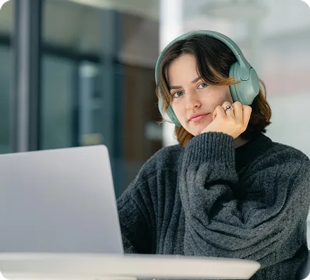 Mujer en un escritorio mirando a la camara con audifonos